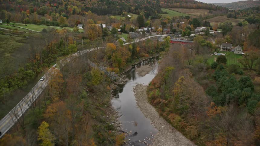 A small river crossing a rural town with a red bridge