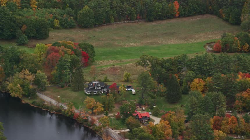 Aerial view of house near river in rural area with fall colors