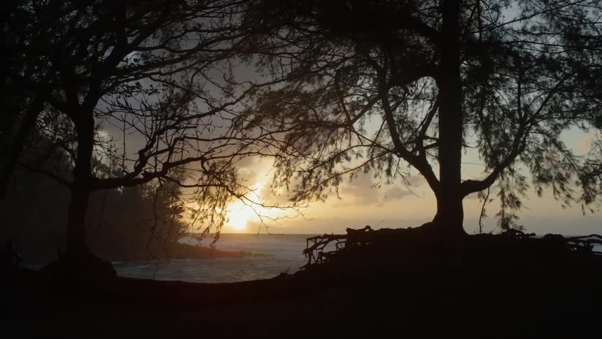 The sun is setting in the distance by the shore