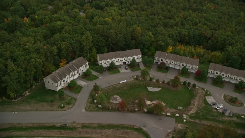 A sub urban town with few buildings surrounded by trees