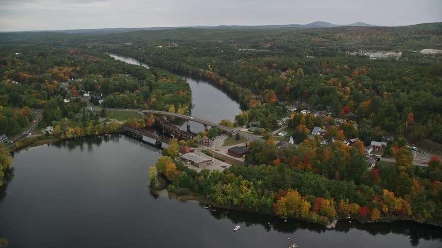 Aerial of a suburban neighborhood with forest and river during sunset