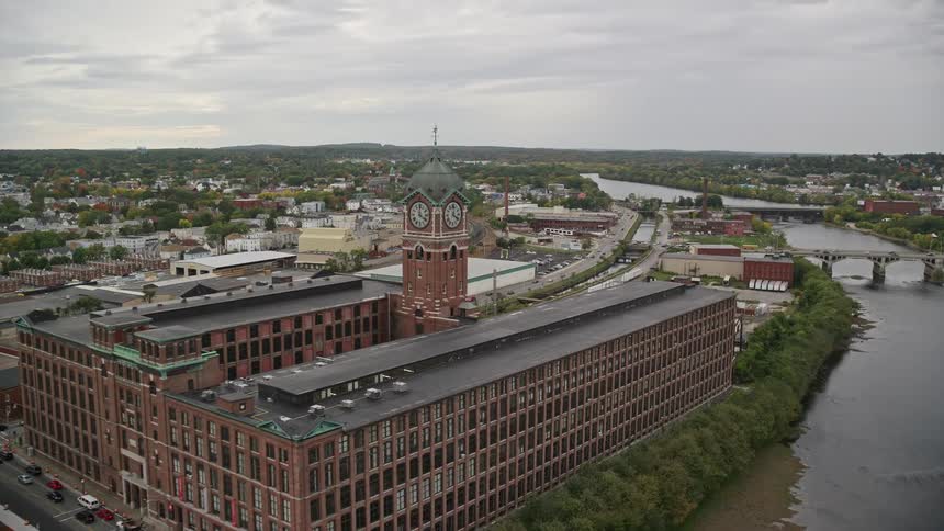 Clock tower and buildings near river in fall on cloudy day