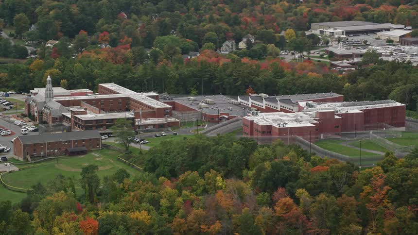 A building that looks like a factory with a parking lot surrounded by trees and other structures