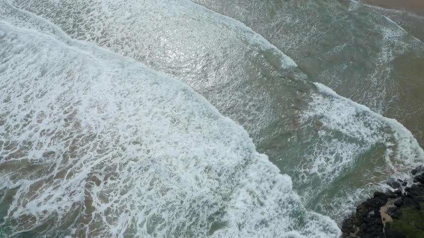 Aerial view of small waves coming ashore