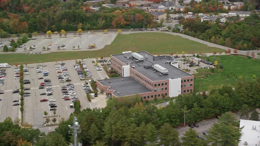 Aerial view of campus and parking lot surrounded by trees in fall color
