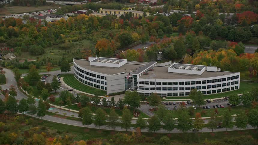 Aerial view of a mirrored building in an urban city with abundant tree vegetation