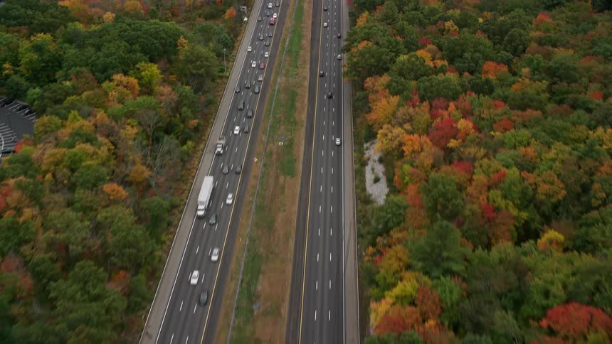 Traffic flows through woods with fall foliagenear office building