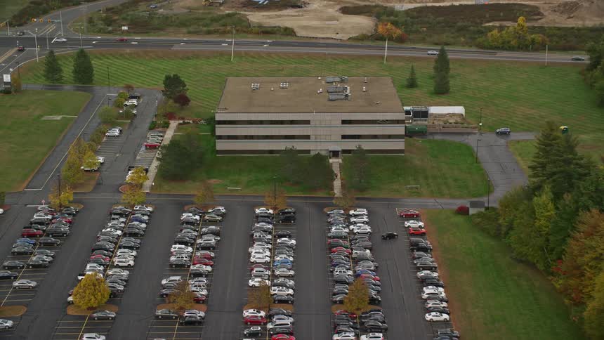 Aerial view of a parking lot filled with cars and a building