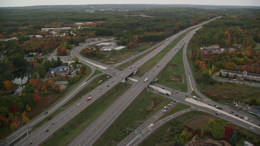 An aerial view of a cloverleaf interchange highway surrounded by trees