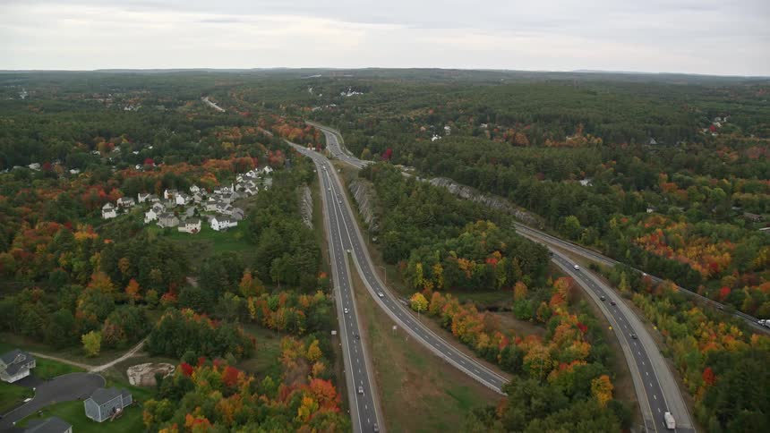 An aerial view of highways between a town and an autumn forest