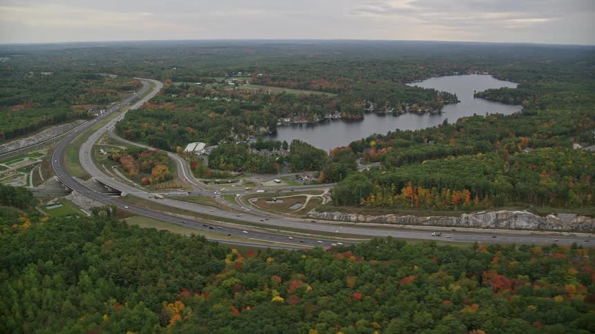A highway with many cars that passes close to forests and a river