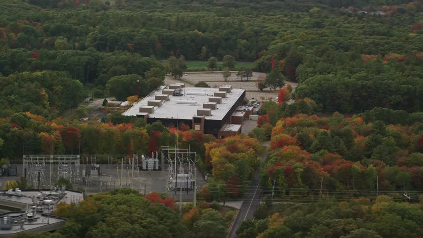 Forest of trees with fall foliage surround utility station and power lines