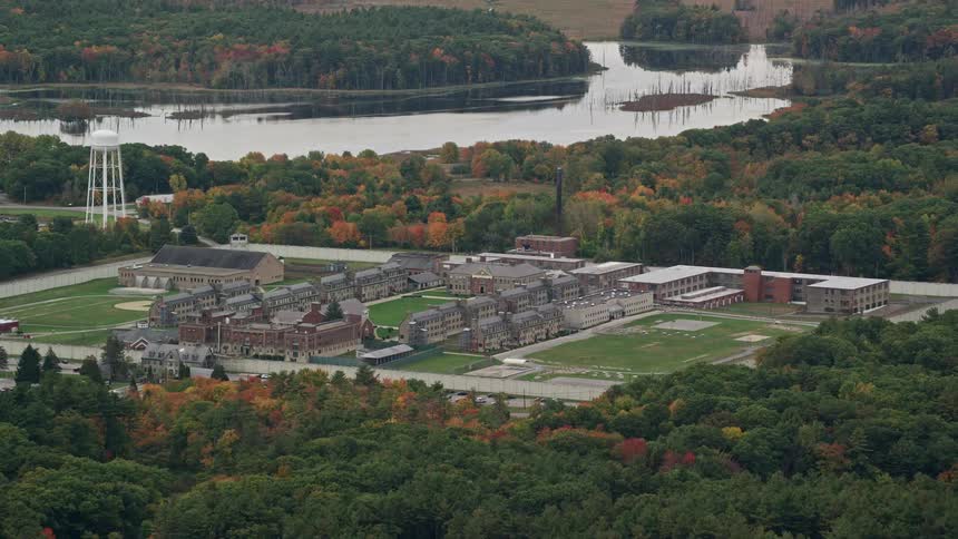 An aerial panorama of a vast area with buildings and pavilions amidst a forested area and lakes