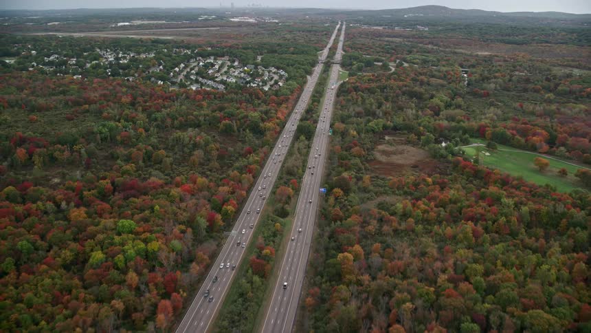 An aerial view of highways cutting through an autumn forest stretching out into the horizon
