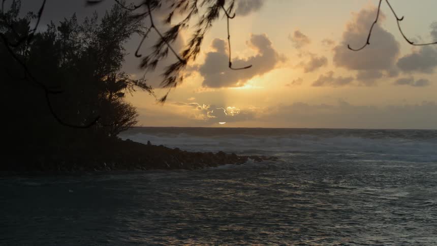 The water is rough near the shore at sunset