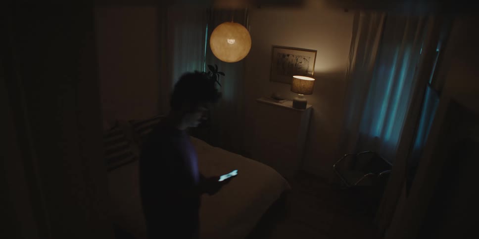 Man views tablet while walking into dimly lit bedroom at night