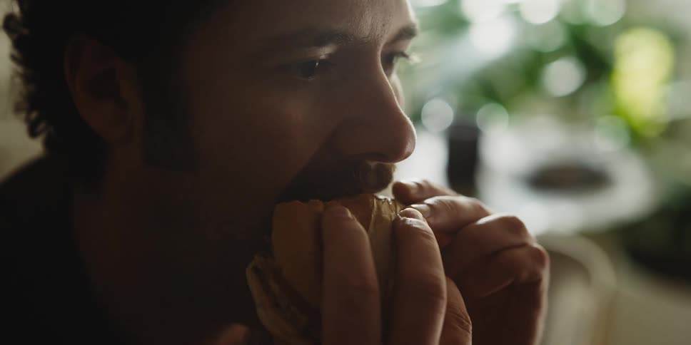 Closeup of a man eating a sandwich with both hands