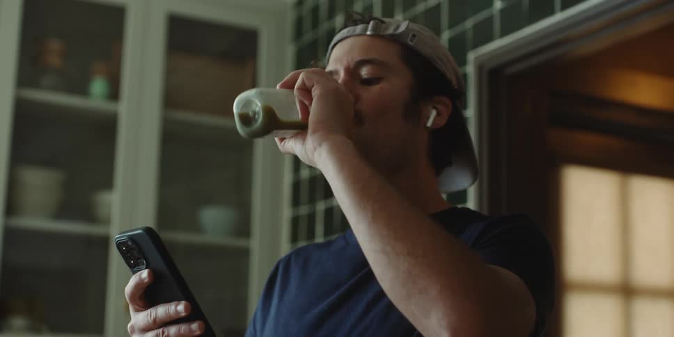 Portrait of a man drinking while looking at his cell phone
