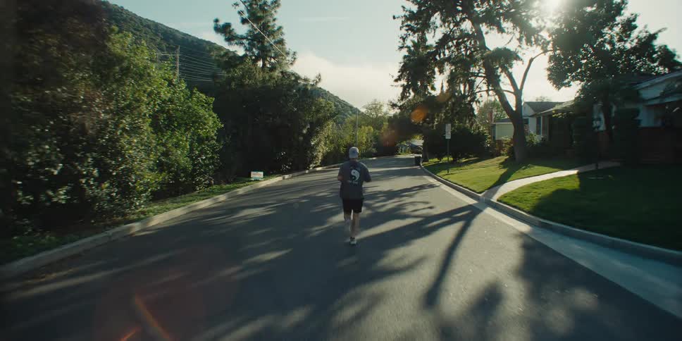 Man running with his back to the viewer in a residential neighborhood street