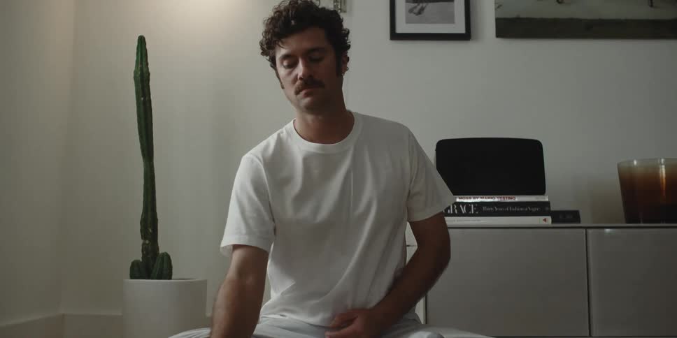 A man in a yoga position when he touches his phone and gets up