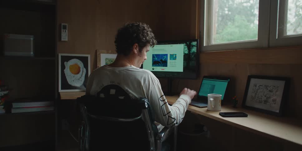 A man working from home using a computer and laptop
