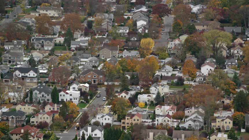 Aerial view of a suburban neighborhood with a dense array of houses interspersed with trees in a palette of autumn colors