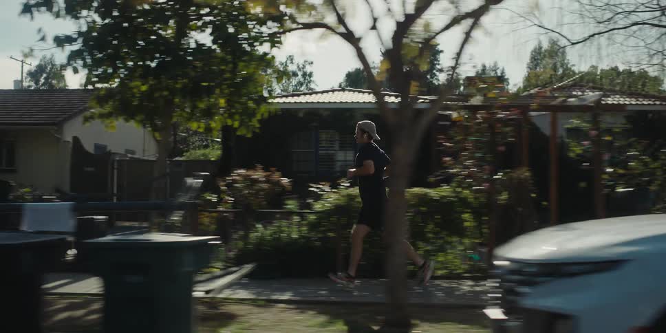 Man wearing a cap t shirt and shorts runs down the street
