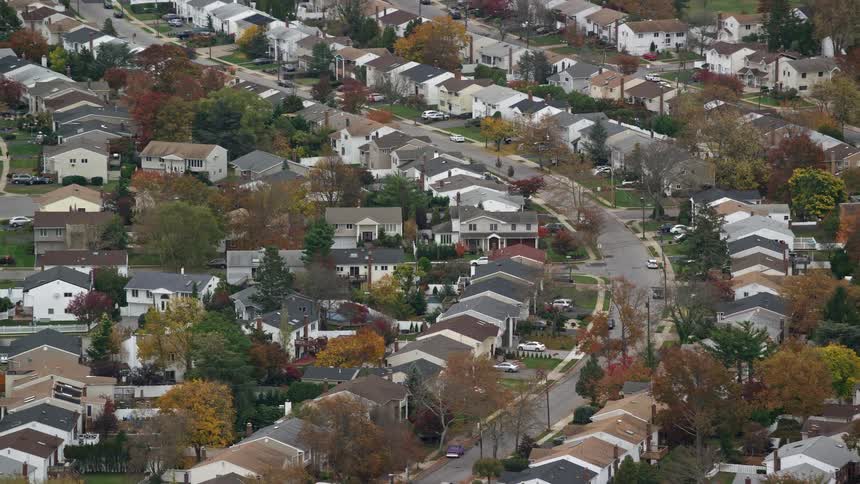 An aerial view of a suburban neighborhood with neatly arranged homes and trees with autumn leaves