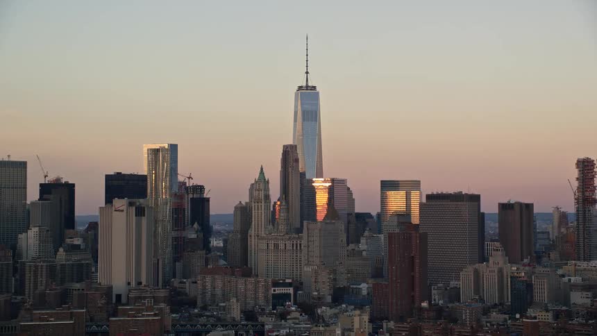 One world trade center towers over surrounding skyscrapers against a red tinted horizon