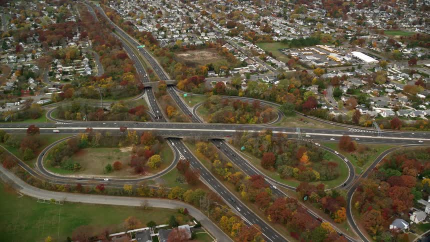 Traffic moves steadily along the seafordoyster bay expressway passing through suburban areas adorned with trees displaying red and gold leaves in the vibrant colors of autumn