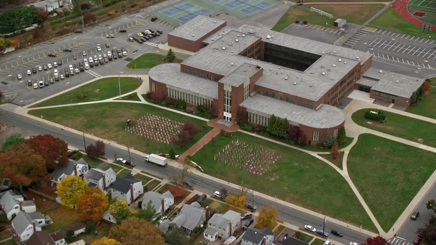Aerial view of a school with a tennis court and baseball field in a neighborhood