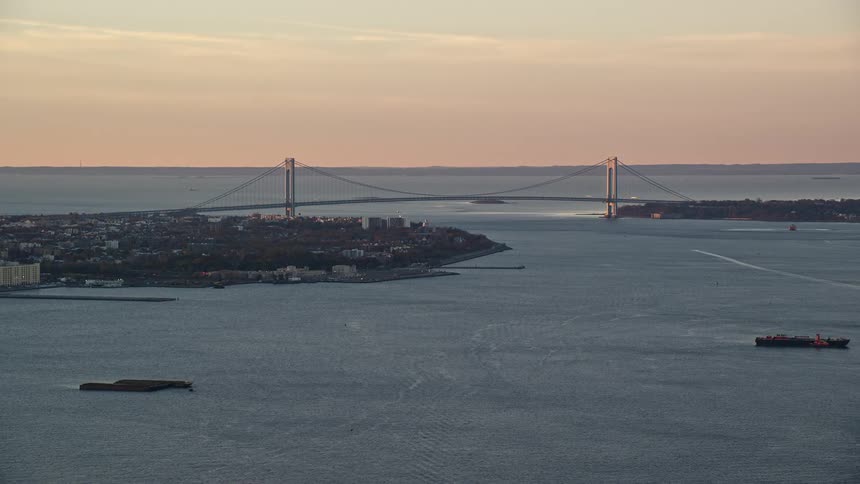 Aerial view of a coastal city with a bridge connecting the cities under a dawn sky