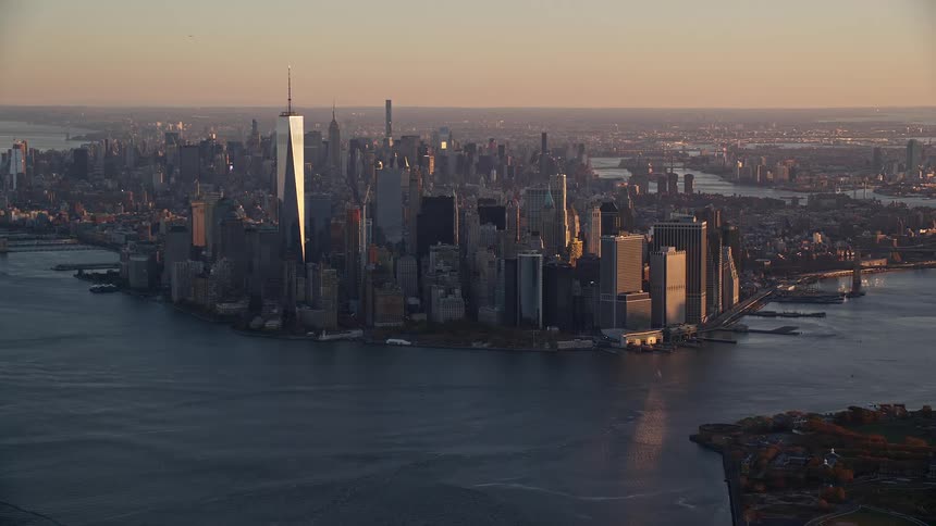 Aerial view of a city skyline near a large body of water during early evening light