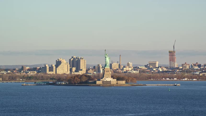 Statue of liberty sits across from urban waterfront