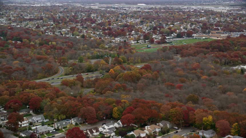 The suburbs of a city with many trees that have red leaves due to the season