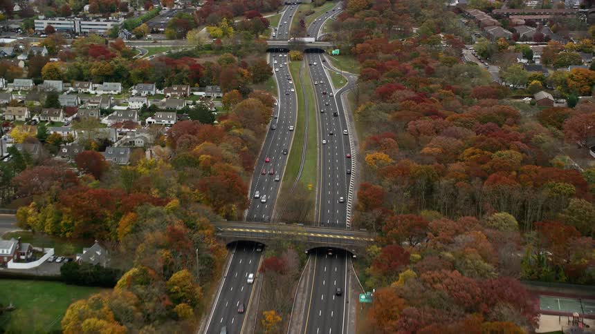 A high way passing beside an urban area with linking bridges as cars go by to and fro