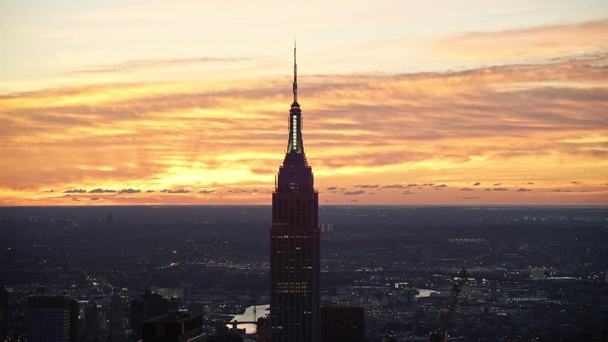 Empire state building being silhouetted against the sky at sunset