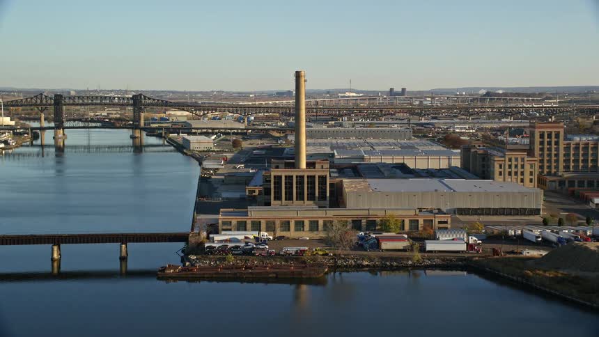 An aerial view of a waterfront factory with smokestacks