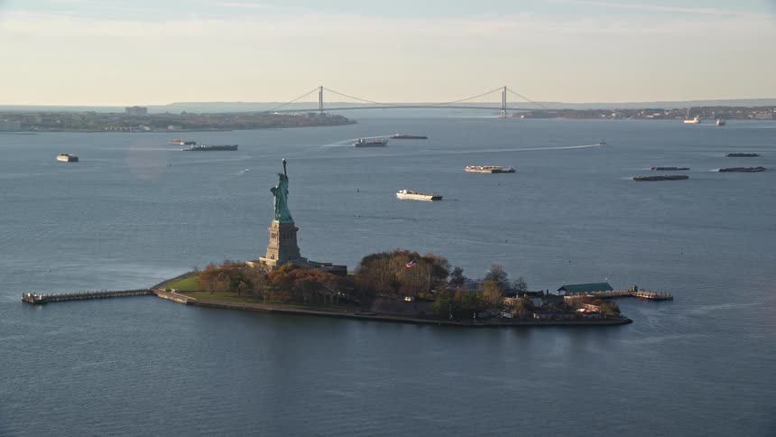 An aerial view of the statue of liberty on liberty island with ships sailing across the water