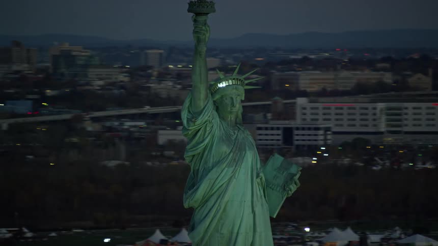 An aerial view of the statue of liberty and the evening skyline