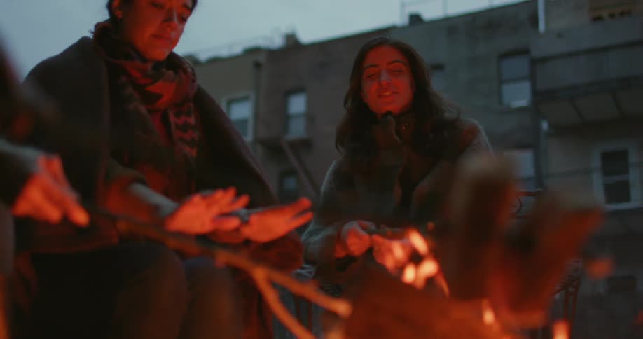 People cook their food on a campfire and warm their hands