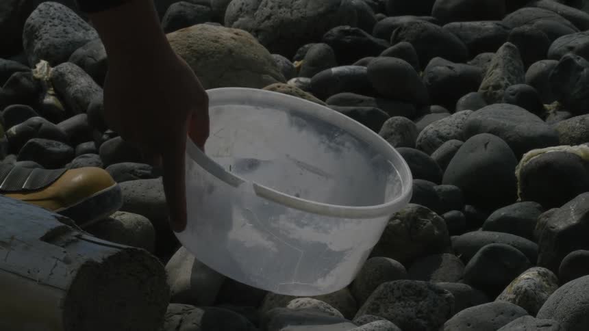 Man wearing yellow boots cleans up the oceans beaches from plastic
