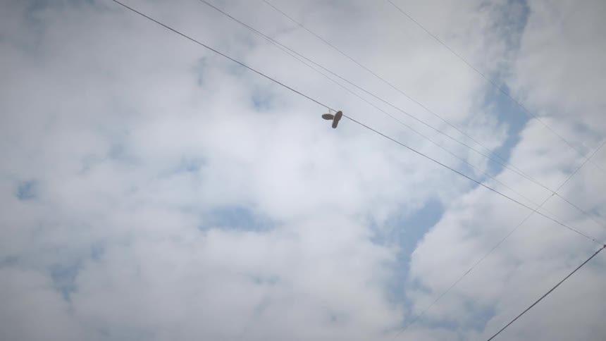 A pair of shoes hanging from an electrical wire