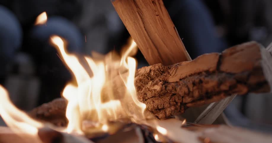 A camp fire burning pieces of wood at night