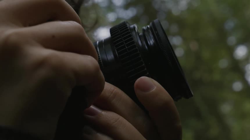A person rotating a camera lens using their fingers