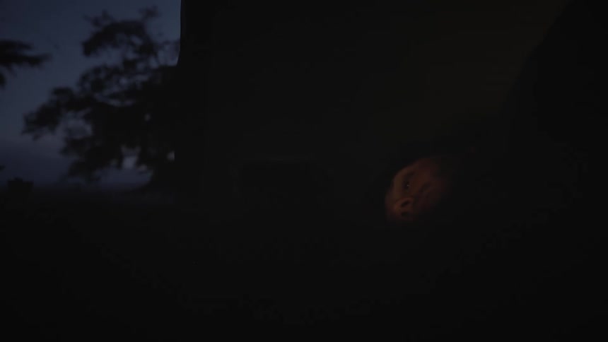 Man lying down and using a cellphone in an outdoor setting during the night