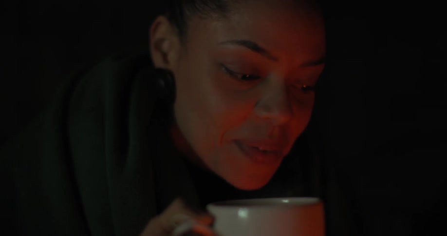 A woman drinks from a mug at night