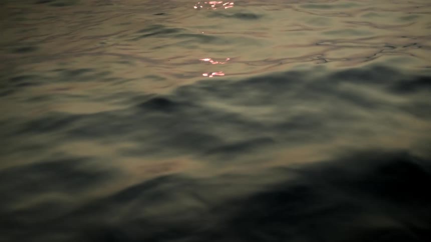 Closeup of calm sea waves with the morning suns reflection