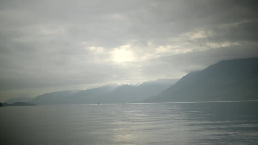 The river is surrounded by mountain with a boat seen from a distance