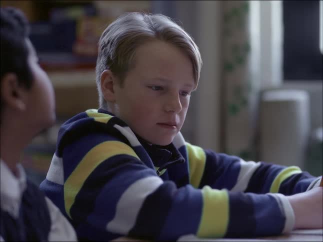 Child looking to the side suspiciously thinking their classmate is peeking at their test